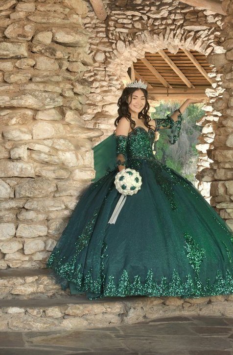 Quinceañera in an emerald green gown with flowing train at a stone pavilion