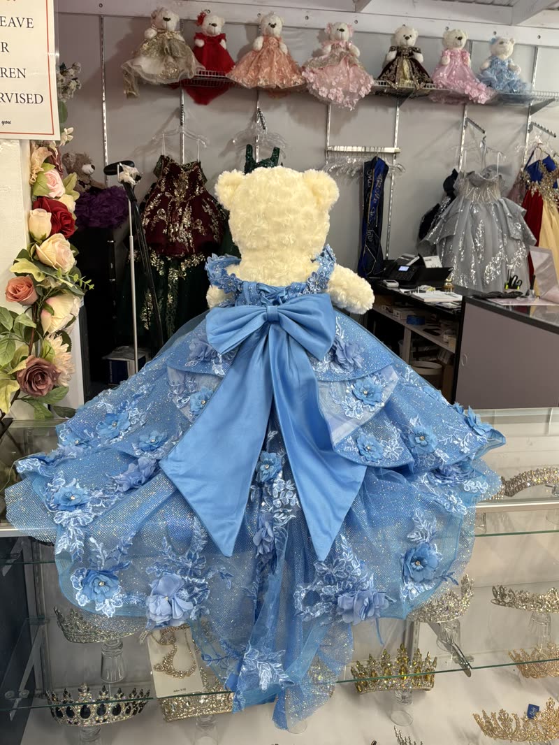 Boutique wall of mini teddy bears in tiny quinceañera dresses beside crystal crowns