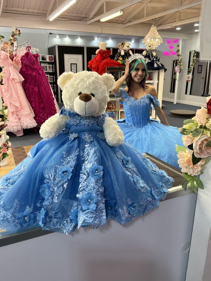 Quinceañera in a light blue gown with a giant teddy bear wearing a matching blue dress
