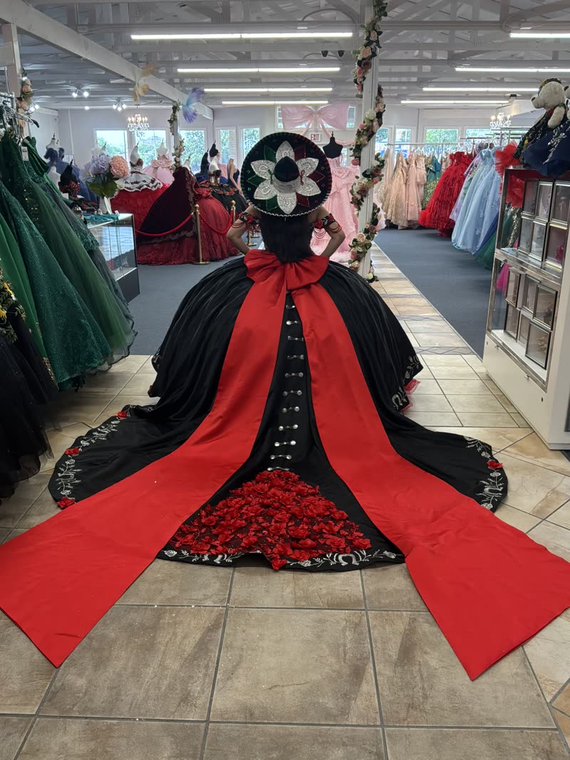 Black charro quinceañera gown with a red satin train lined with roses and a matching embroidered sombrero