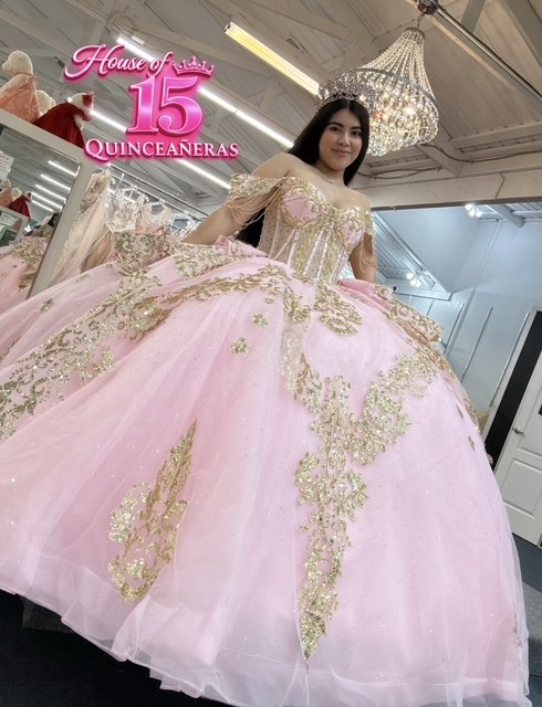 Quinceañera in a blush pink ball gown with gold sequin appliqué in the House of Quinceañeras showroom