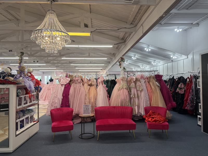 House of Quinceañeras salon with chandelier, racks of pink gowns and hot pink loveseats